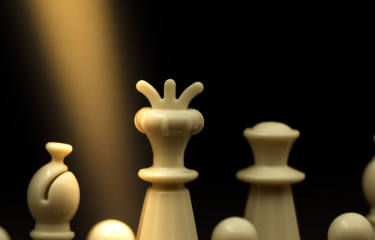 Cream chess pieces lit against a black background